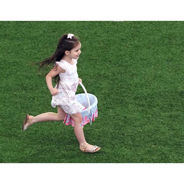 一个拿着复活节篮子跑下球场的女孩